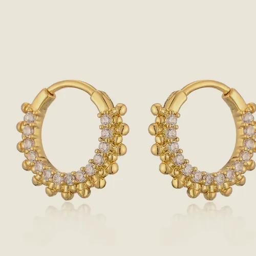 Aretes de aro ovalado dorado con perlas pequeñas en el borde interior.