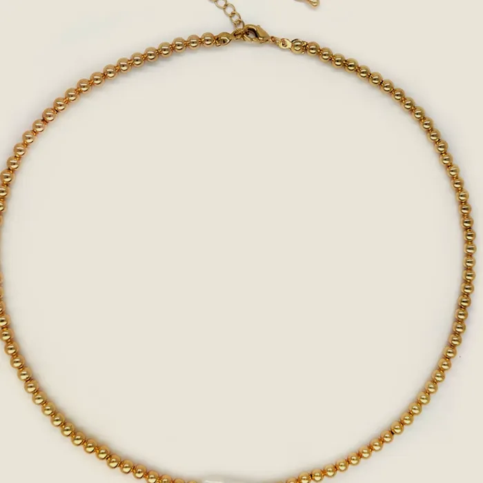 Collar de cadena dorada de eslabón redondo con una perla alargada montada en el frente.