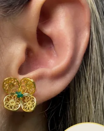 Arete de flor de filigrana puesto en la oreja.