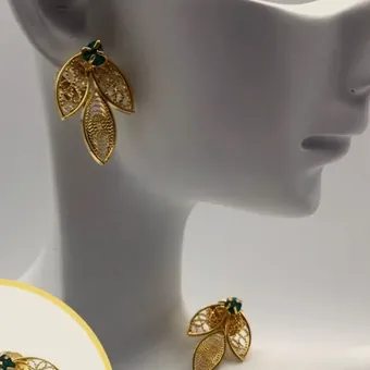 Gold-tone filigree leaf earrings on a white bust.