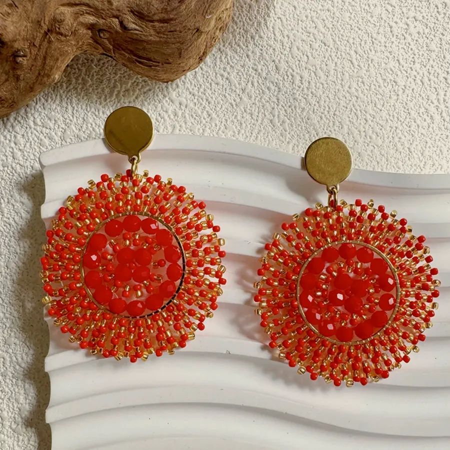 Large earrings of a red woven thread disc with a pointed rim, hanging from a gold-tone stud.