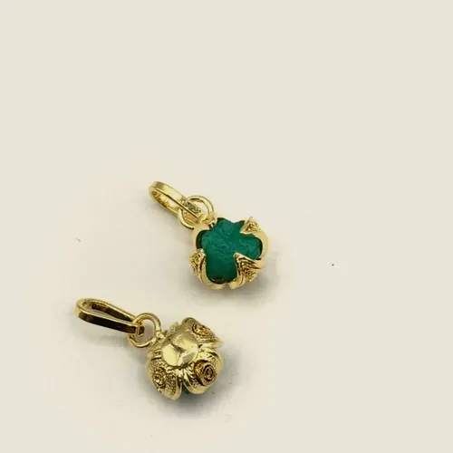 Dos dijes de trébol, uno con esmeralda en bruto verde y otro dorado liso.
