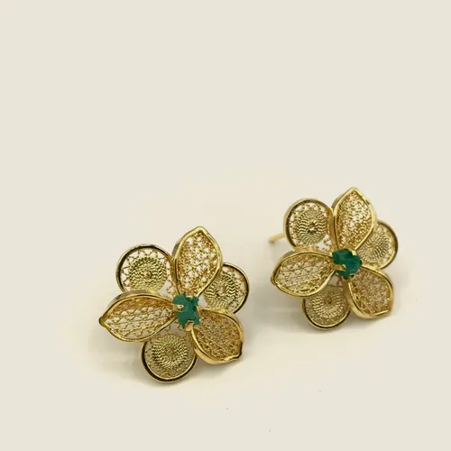 Aretes de filigrana dorada de cuatro pétalos con esmeralda en bruto en el centro.